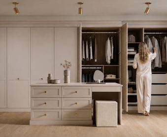 a fitted wardrobe in a room with a storage island in the middle